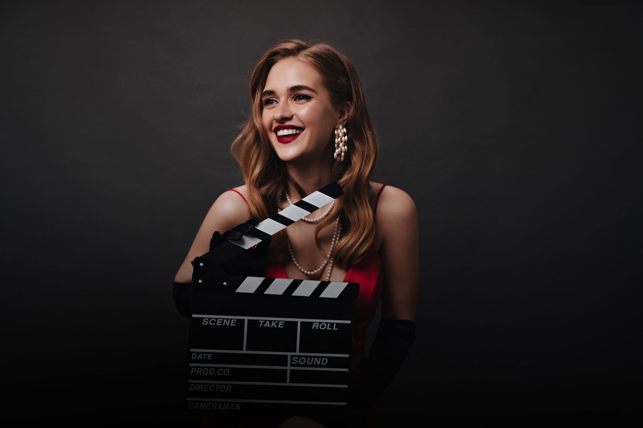 white lady smiling holding clapperboard+